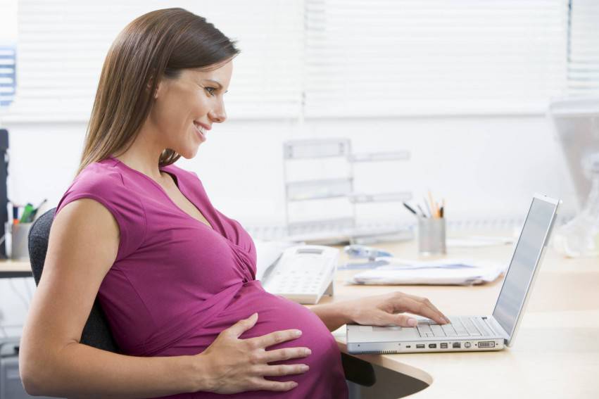 Donna incinta al computer in ufficio