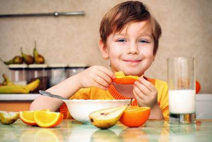 Bambino sorridente mangia soddisfatto frutta e yoghurt