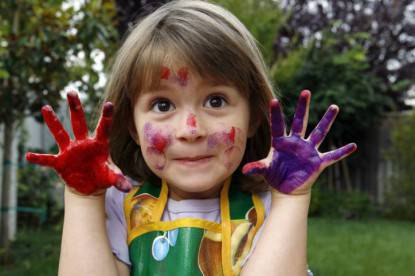 Una bambina mostra le sue mani colorate
