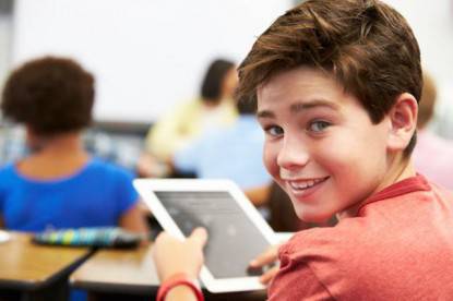 Un bambino sta usando un tablet in classe (registro elettronico)