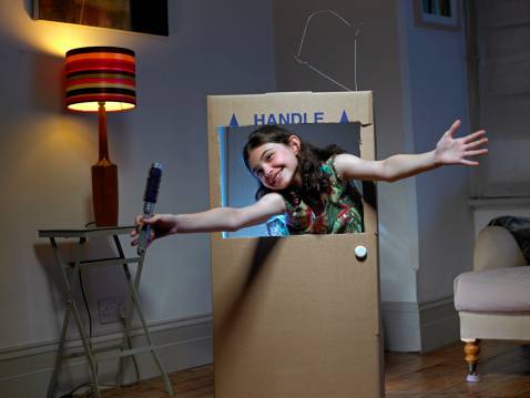 Girl playing in cardboard box TV