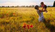 Woman smiling in a poppy field with her babby girl.