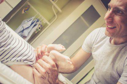Happy Playful Father Changing Baby's Diaper.