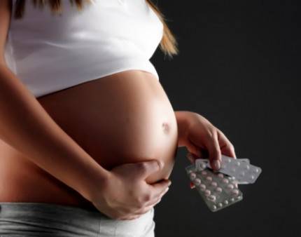 Donna in gravidanza con in mano dei blister di medicinali