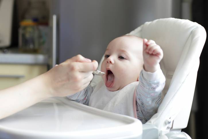 Bambino di poco mesi imboccato con le prime pappe