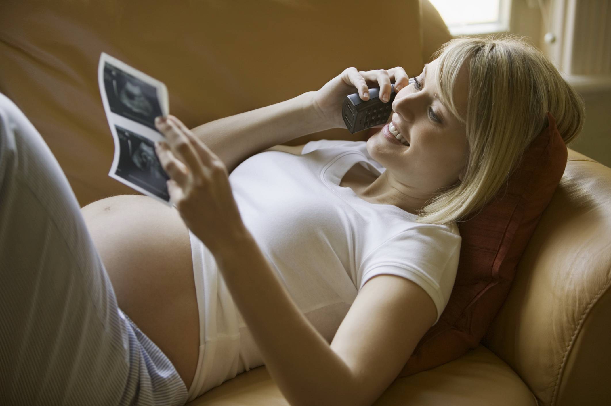 donna incinta sorridente osserva l'ecografia del suo bambino