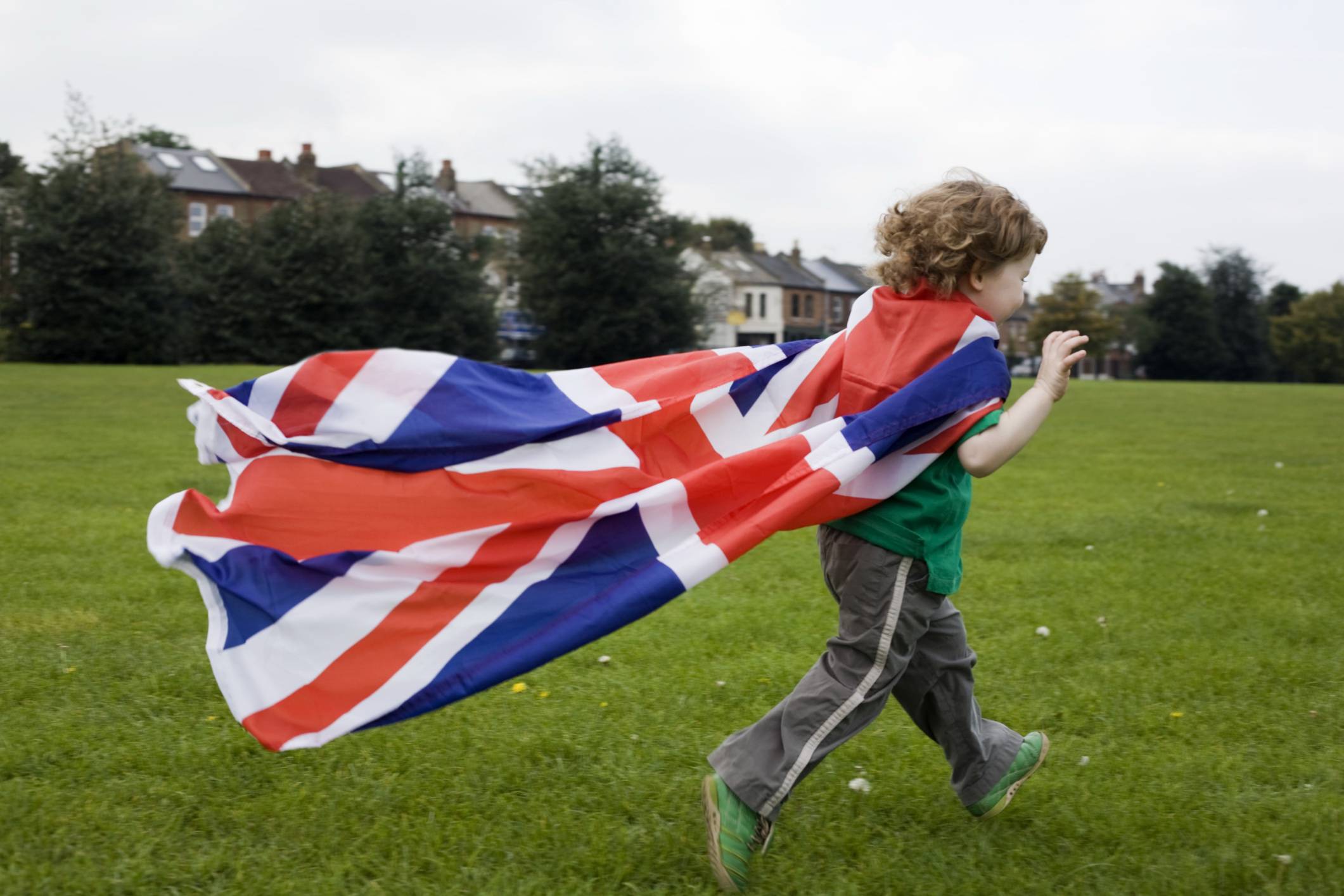 Ragazzo corre su prato con bandiera inglese come mantello