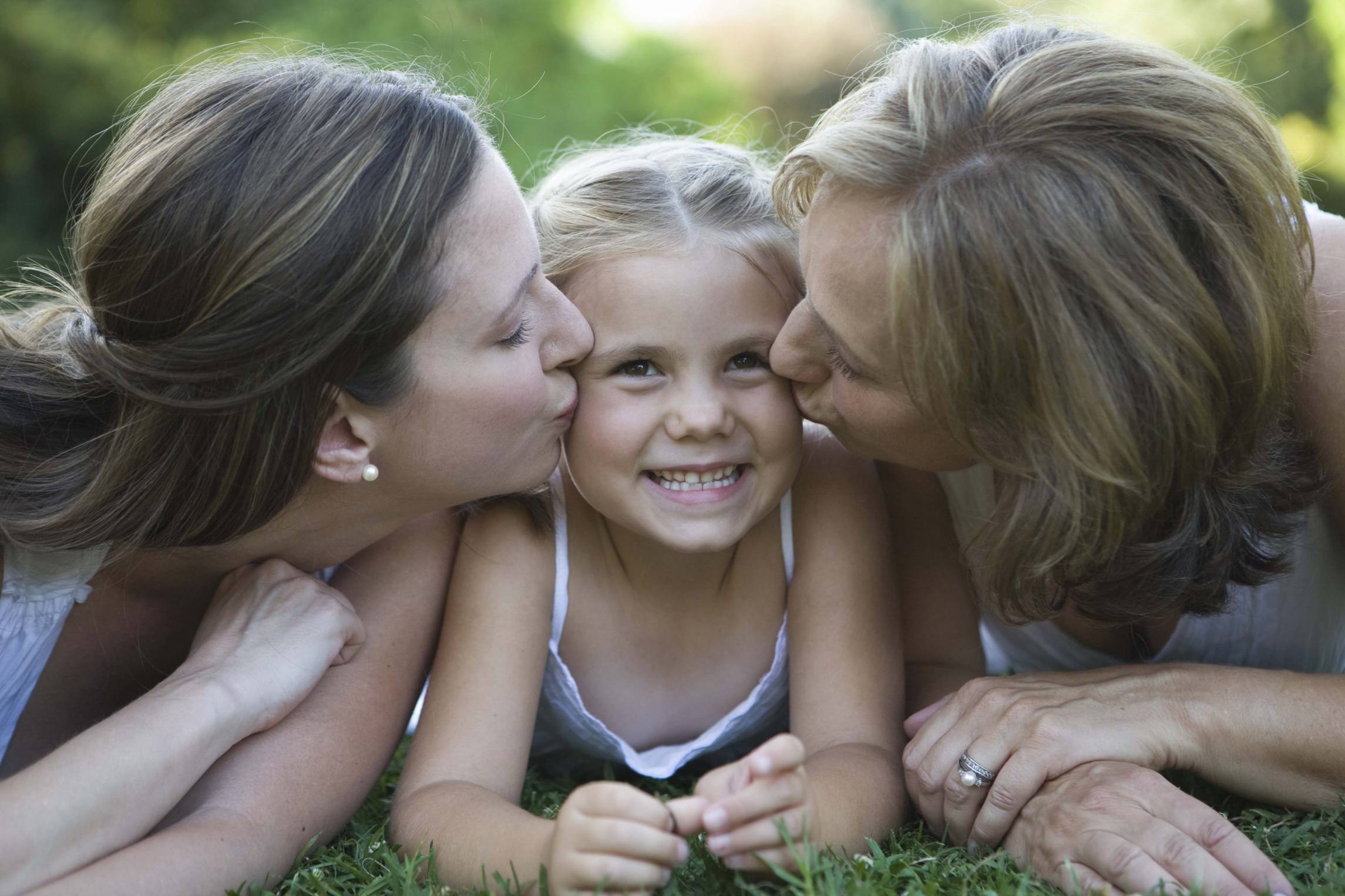 bambina baciata da mamma e nonna