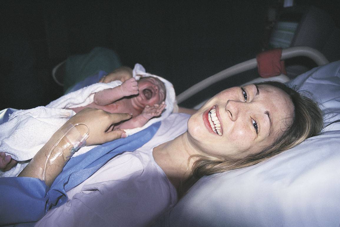 Madre felice con bambino appena nato nel letto