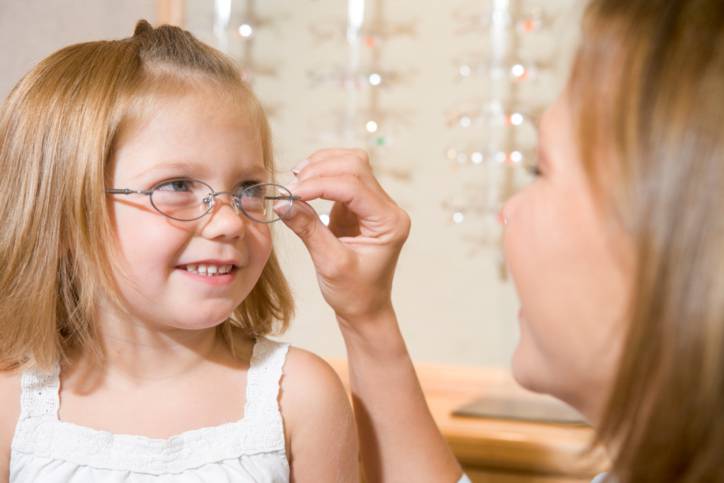 donna che prova gli occhiali a una bambina dall'oculista