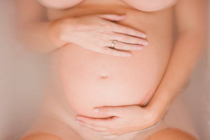 Donna incinta in acqua, primo piano della pancia