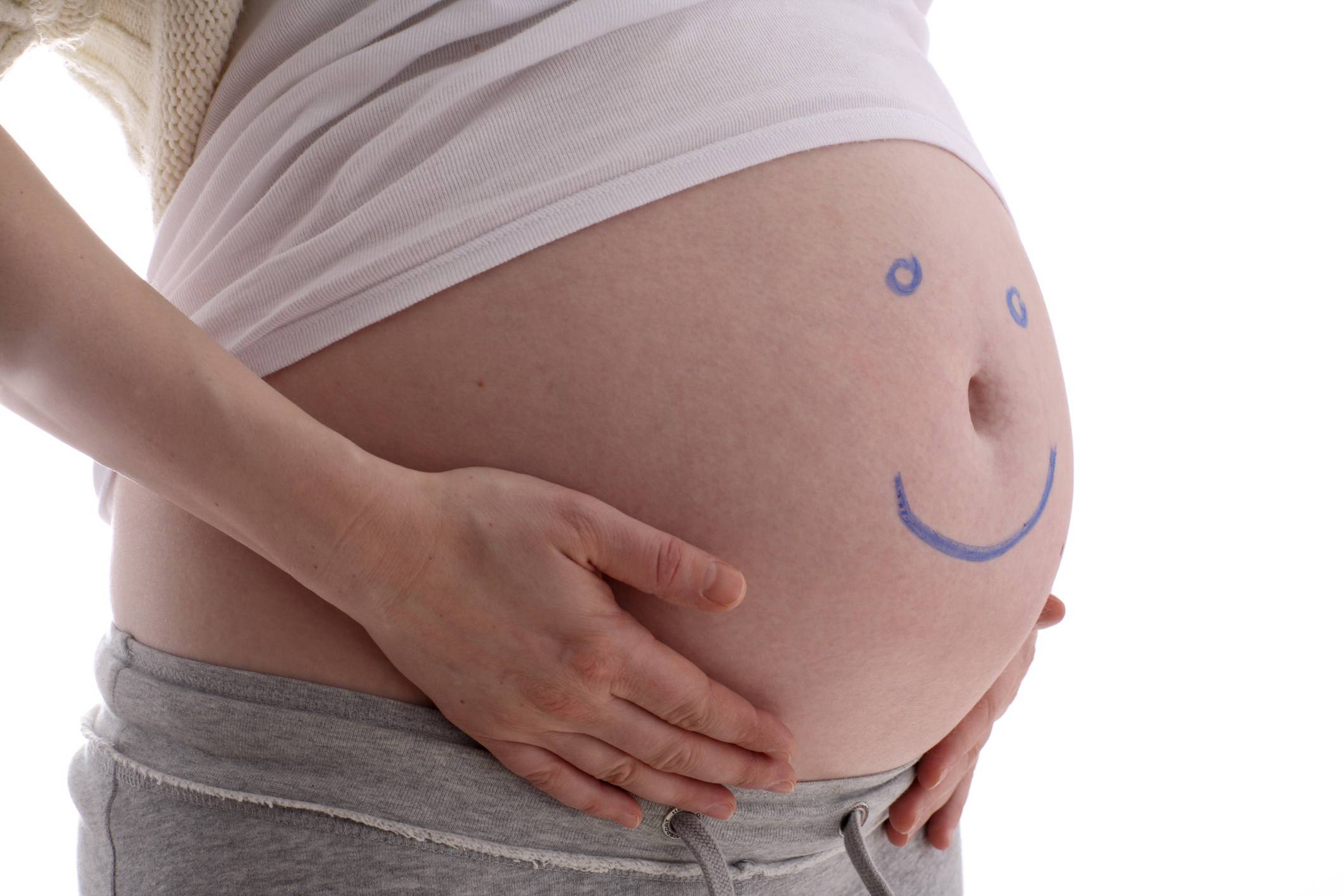 Pancia di donna incinta con sorriso dipinto sulla pelle
