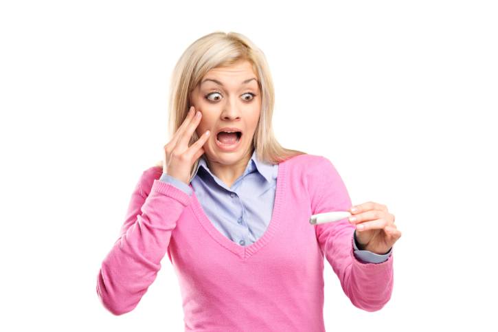 Donna spaventata con in mano un test di gravidanza positivo