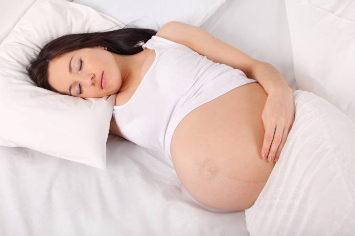 Donna incinta al nono mese, sdraiata nel letto