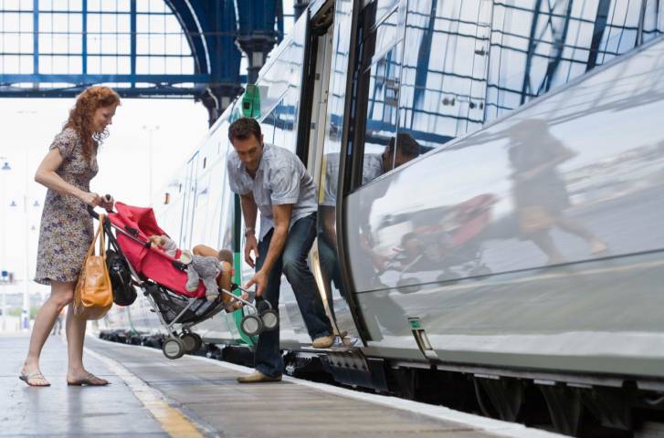 Famiglia con passeggino che sale sul treno