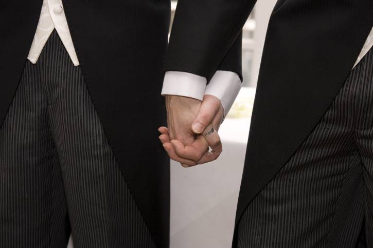 Due uomini si tengono per mano durante matrimonio