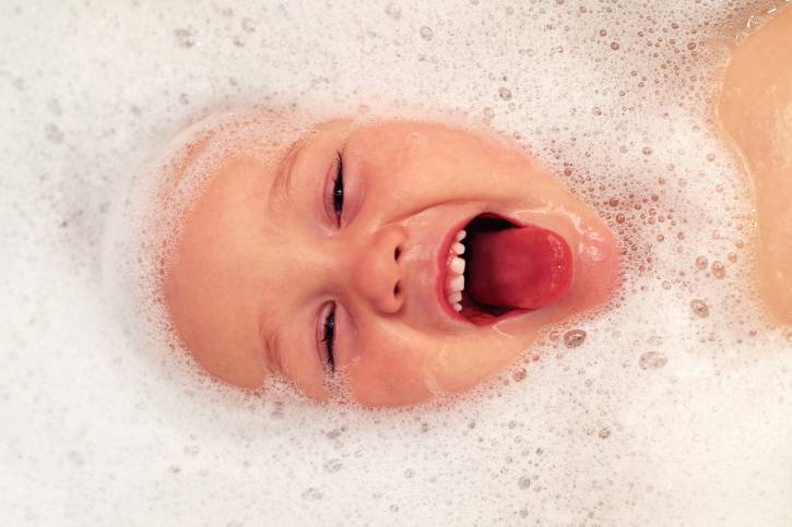 bambino sorridente tra le bolle nel bagnetto