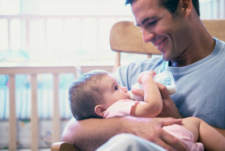 Papà che da' il biberon al figlio