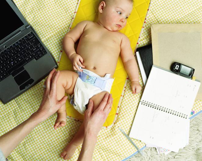 mamma cambia pannolino su scrivania di lavoro