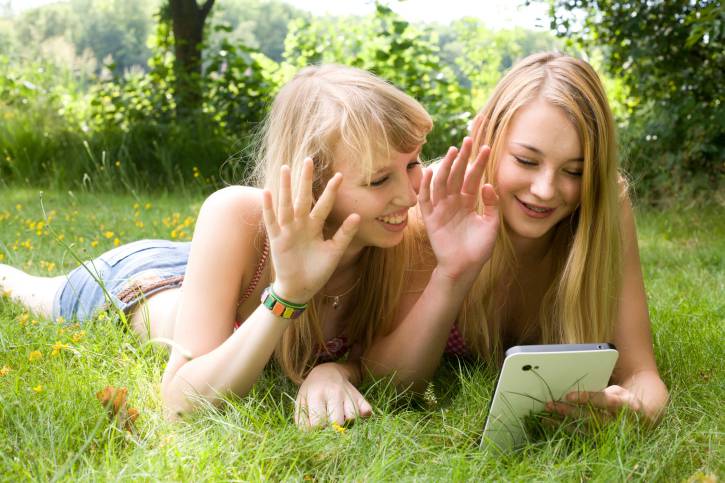 Ragazzine sull'erba che videochiamano con un tablet