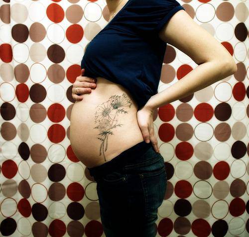 Donna incinta con tatuaggio sulla pancia