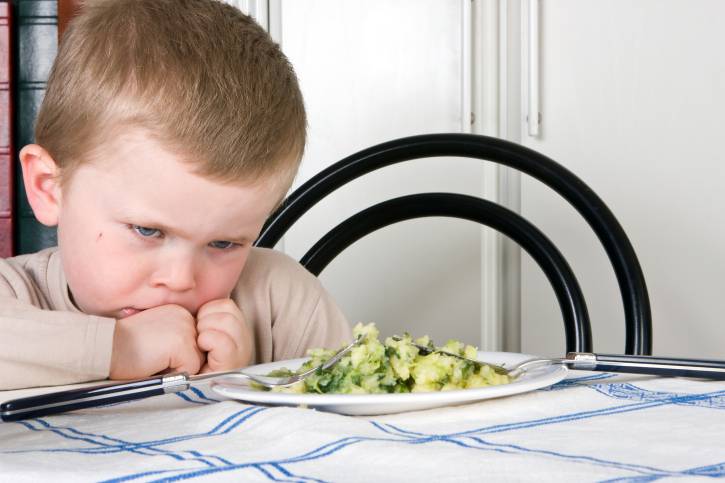 Bambino capriccioso di fronte a un piatto