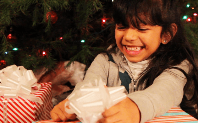 bambina sorride scartando un regalo