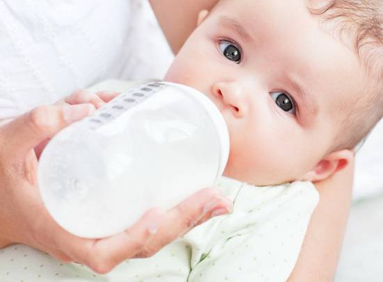 Bambino pochi mesi mentre viene allattato con biberon