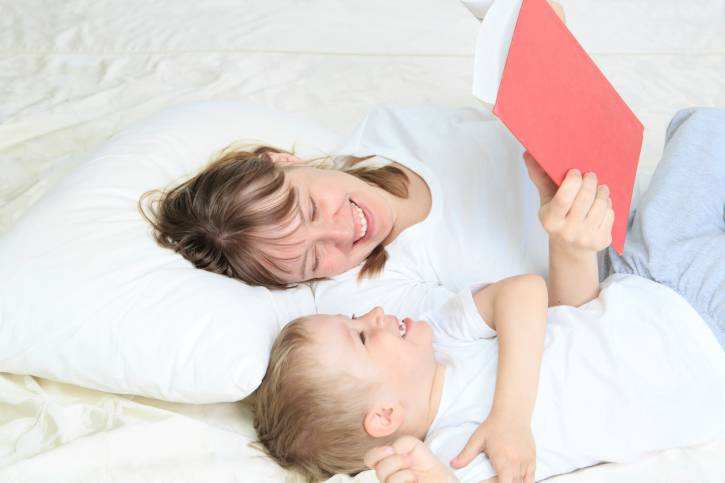 mamma e figlio leggono un libro a letto