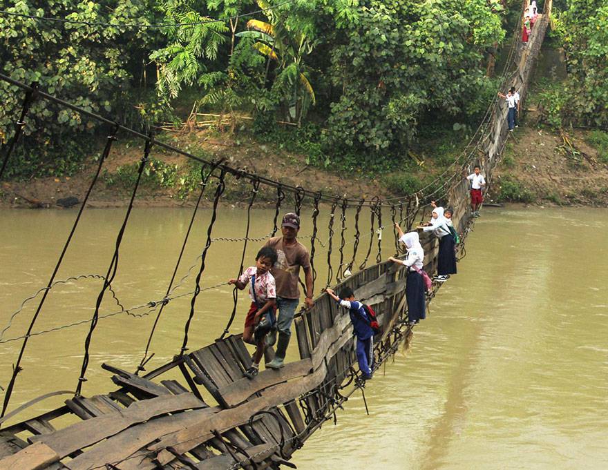 bambini percorrono un ponte sospeso e barcollante su un fiume