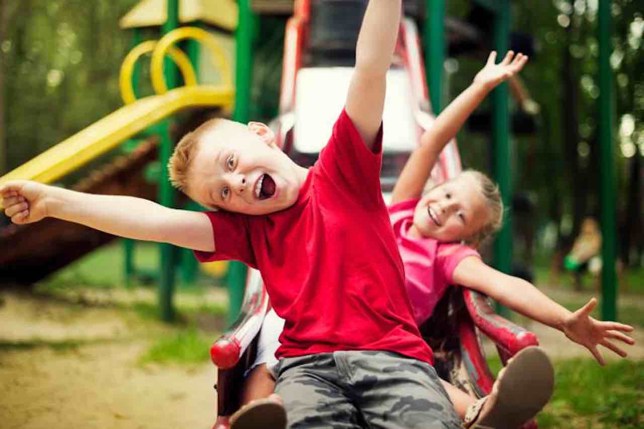 bambini sullo scivolo al parco giochi