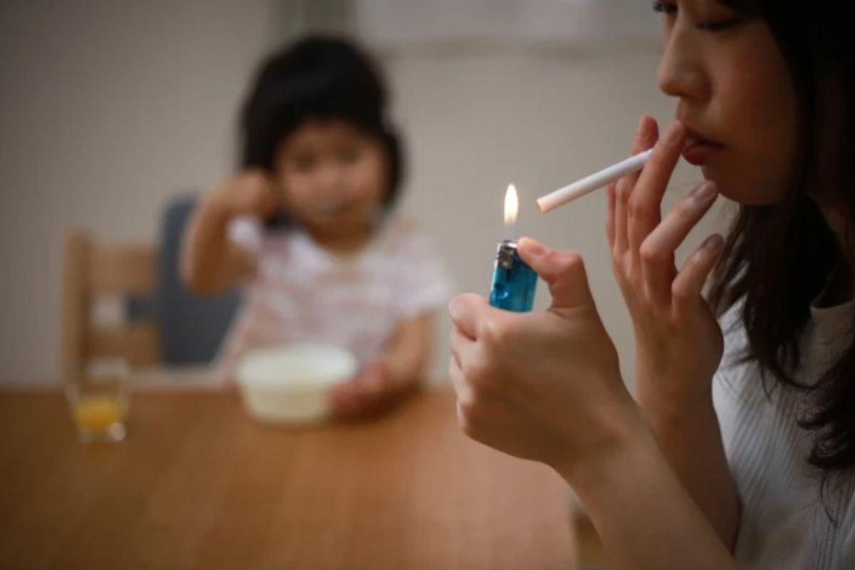 donna accende una sigaretta davanti ad una bambina