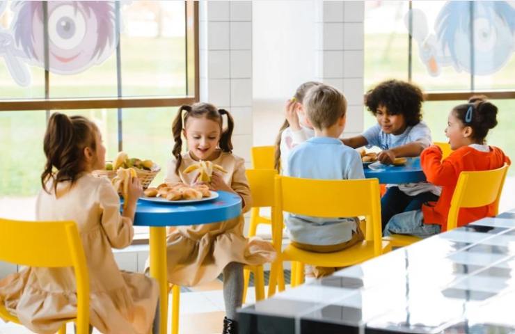 bambini mangiano seduti intorno al tavolo 