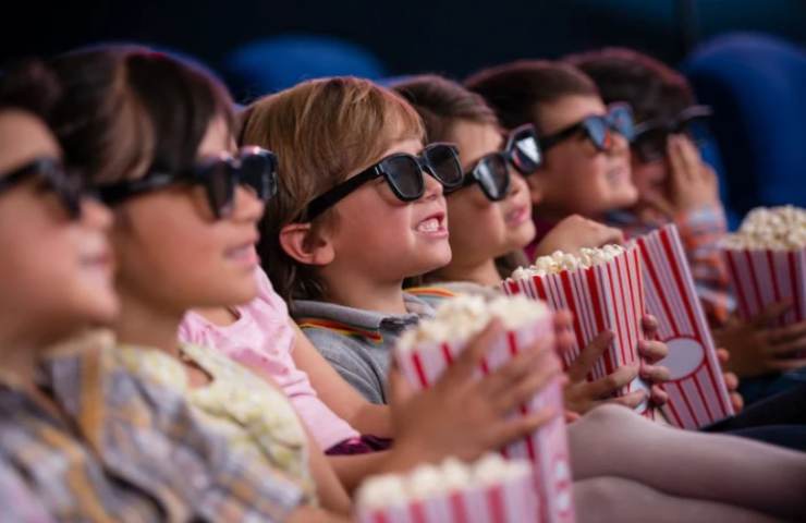 bambini felici al cinema con popcorn e occhiali 3D